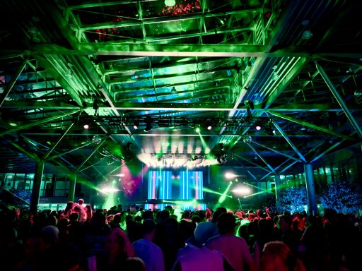 Bunte Lichter und viele Menschen in einer lebhaften Veranstaltungsstätte.