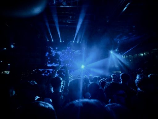 Blaue Lichtstrahlen auf Menge bei einem Konzert, Menschen erleben die Performance.