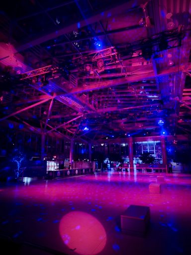 Bunte Lichter in einem dunklen Raum mit futuristischer Atmosphäre und Tanzfläche.