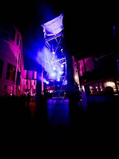 Bühne mit bunten Lichtern und Nebel in einer nächtlichen Umgebung.