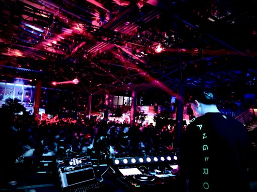 DJ bei einer lebhaften Veranstaltung mit bunten Lichtern und einer großen Menge.